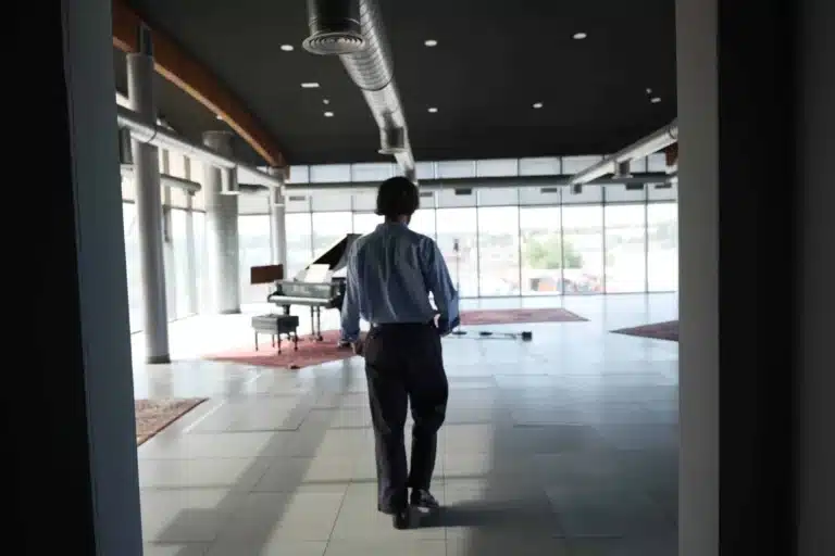 Hombre caminando hacia un piano en un estudio de grabación amplio y moderno.