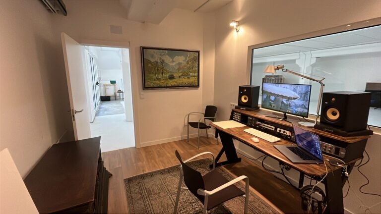 Estudio de grabación profesional con mesa de mezclas, monitores y ordenador.